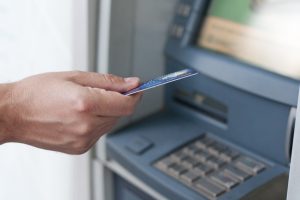 Hand inserting ATM card into bank machine to withdraw money. bus